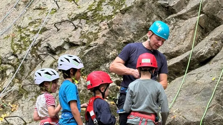 Auf dem Bild sieht man einen Trainer mit 4 Kindern am Fels. Ein Top Rope Seil sit eingehangen, der Trainer bindet gerade eines der Kinder ein. | © Sven Hami